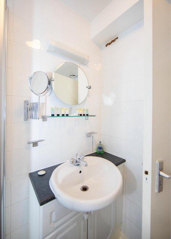 Modern bathroom with round white sink, mirrors, and tiled walls