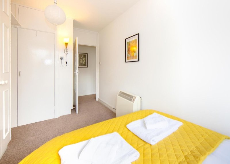 Bright bedroom with yellow bedding, two pillows, ensuite bathroom and framed wall art
