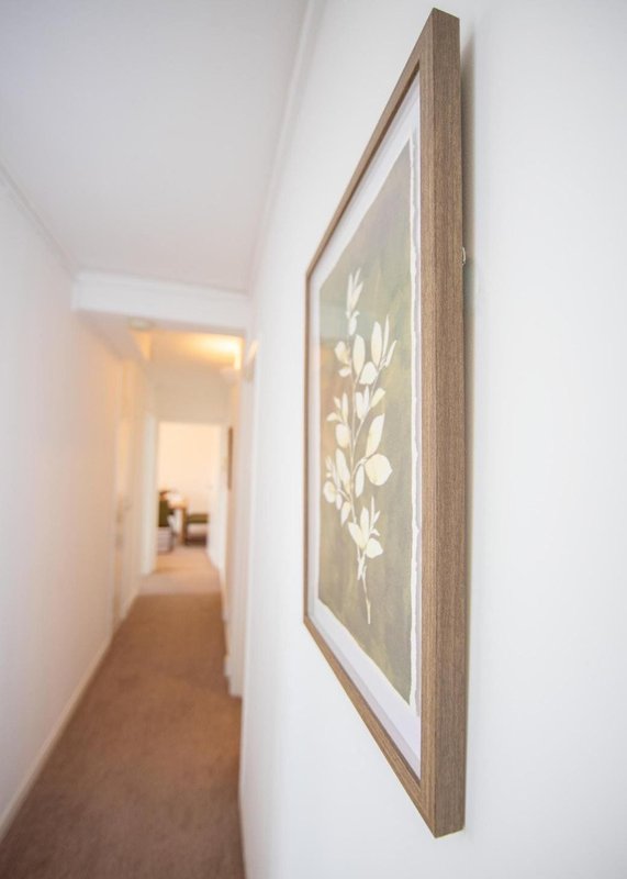 Narrow hallway with framed botanical artwork on wall and open doorways