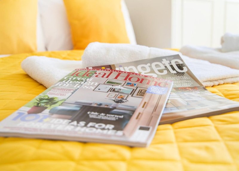 Yellow bedding with white pillows and scattered magazines on bed