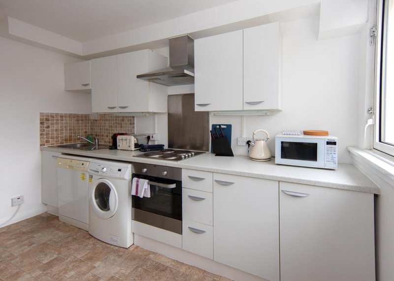 Modern kitchen with white cabinetry, integrated appliances, tiled backsplash and window