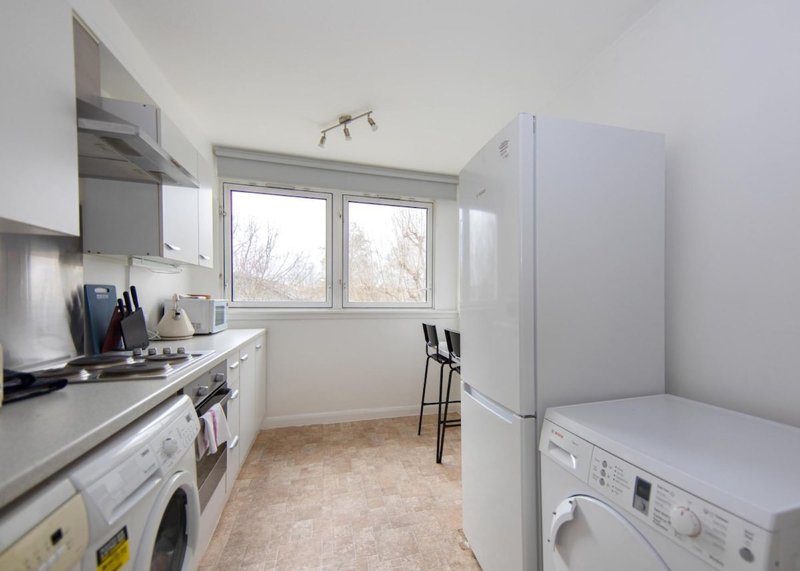 Modern kitchen with white cabinetry, stainless steel appliances, and window overlooking garden