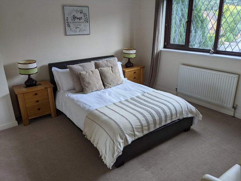 Bedroom with double bed, striped duvet, wooden bedside tables, and leaded windows