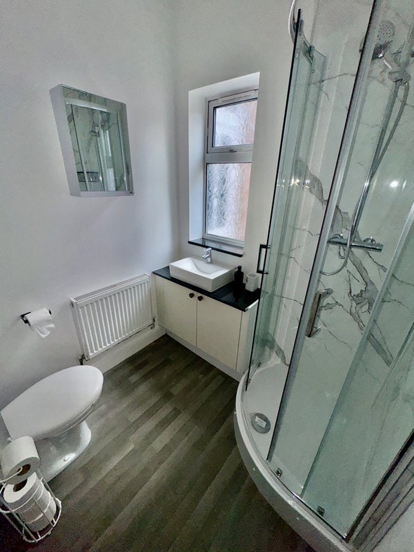 Modern bathroom with toilet, sink vanity, shower cubicle and window
