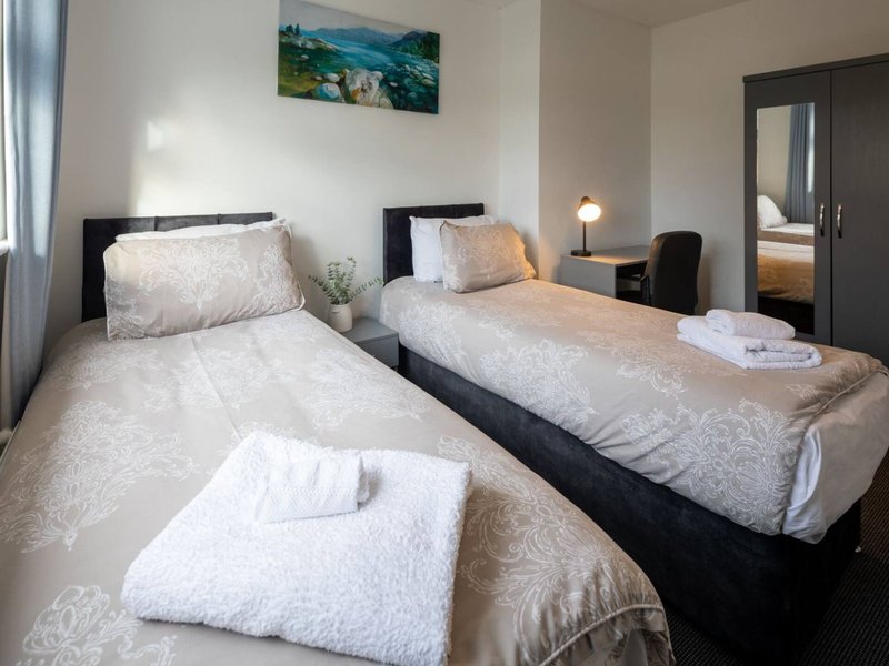 Twin bedroom with two single beds, white bedding, landscape artwork, and modern furnishings