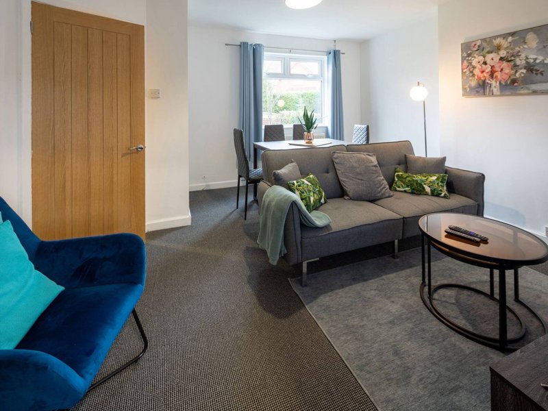 Modern living room with gray sofa, blue armchair, coffee table and window with curtains