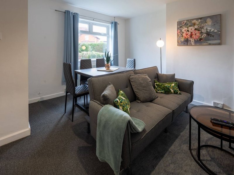 Living room with brown sofa, cushions, window desk, floor lamp and framed artwork