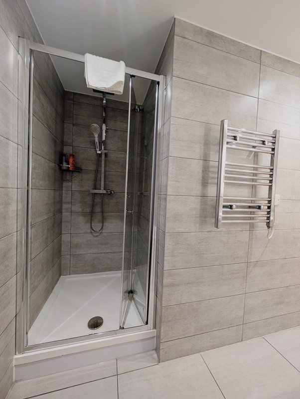 Modern bathroom with walk-in shower, heated towel rail and white tile flooring