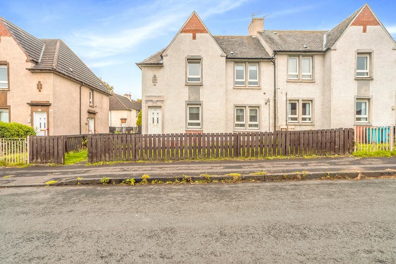 Row of traditional stone tenement buildings with wooden fence and street frontage