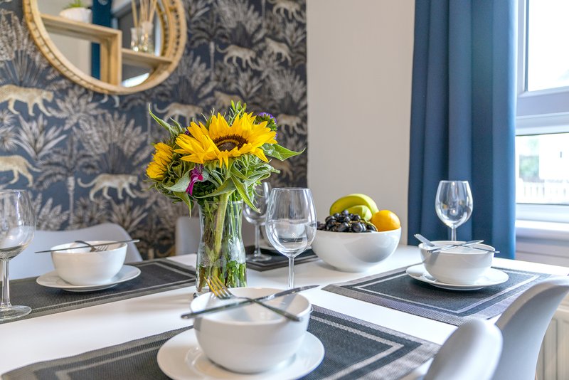 Dining table set with sunflowers, place settings, wine glasses and fruit bowl
