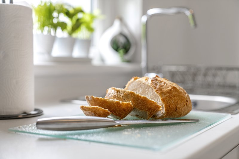 Kitchen countertop with sliced bread, paper towel holder, and potted plant by window