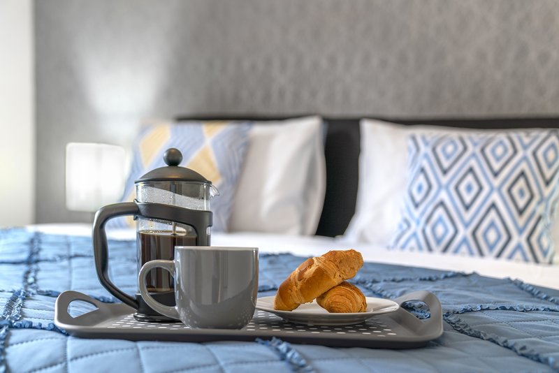 Bedroom with coffee service, croissants and pillows on blue bedding