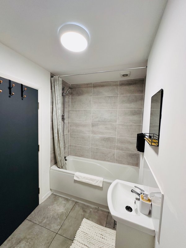 Modern bathroom with bathtub, shower enclosure, sink and recessed ceiling light