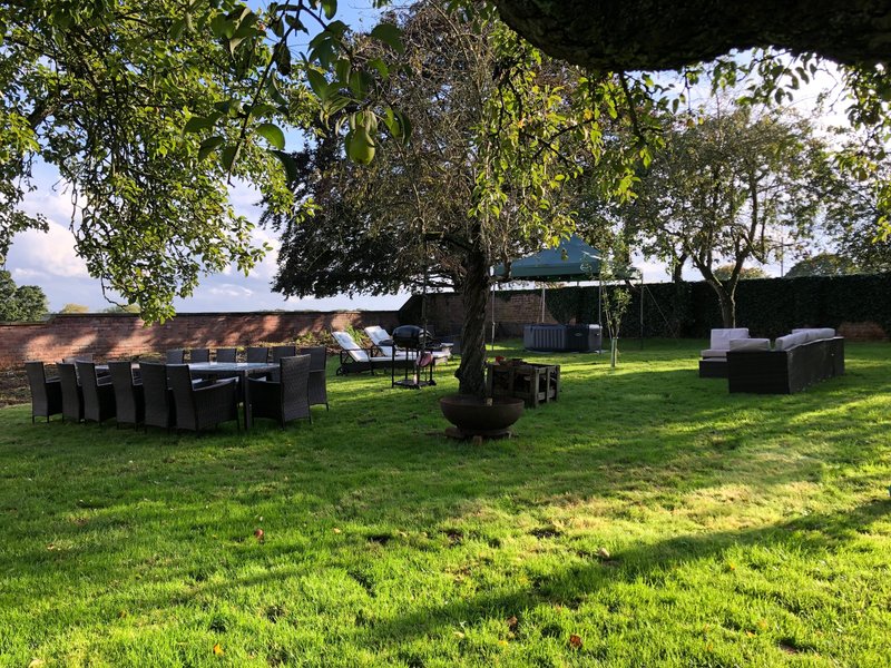 Outdoor garden space with lawn, mature trees, seating areas and landscape boundaries