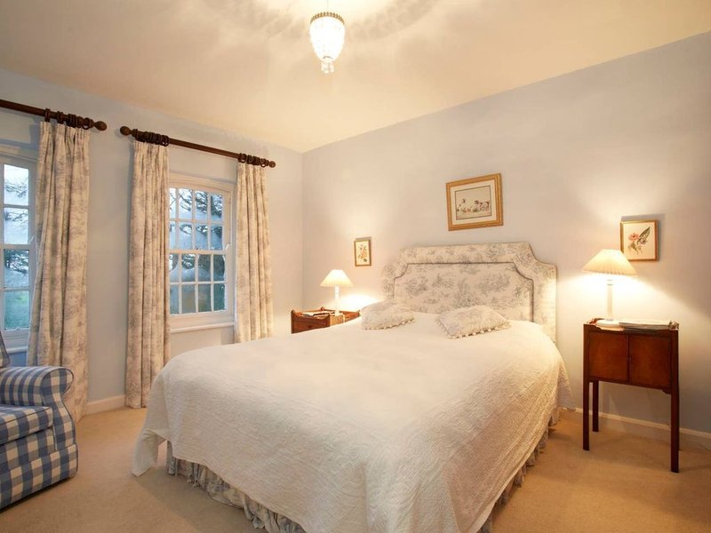 Bright bedroom with double bed, wooden nightstands, cream curtains, and framed wall art