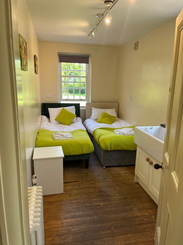 Twin bedroom with lime green bedding, wooden floor, window and track lighting