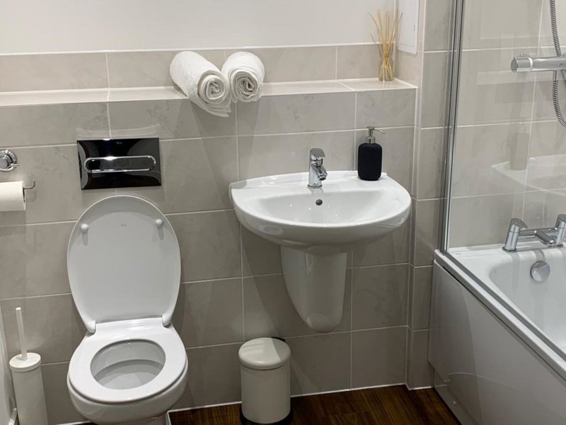 Modern bathroom with toilet, pedestal sink, shower enclosure and tiled walls