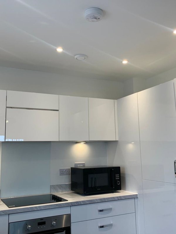 Modern kitchen with white cabinets, black microwave, and recessed ceiling lights