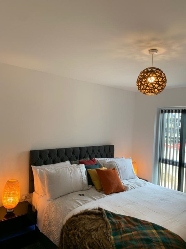 Modern bedroom with double bed, black headboard, pendant lamp, and bedside lighting