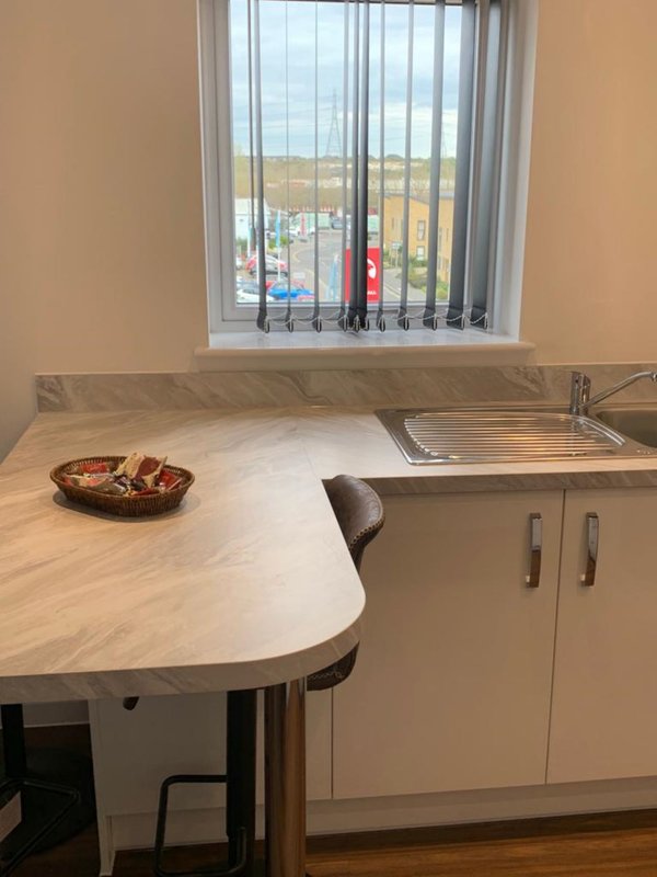 Kitchen with curved countertop, sink, cabinets and window overlooking residential street