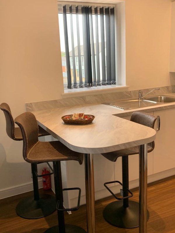 Modern kitchen with white countertop table, two brown chairs, and vertical blinds on window