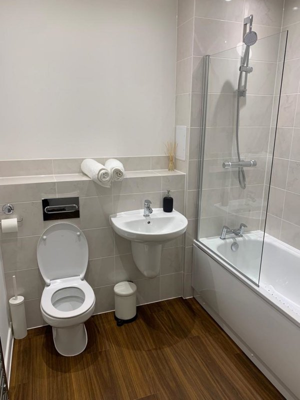 Modern bathroom with toilet, sink, shower enclosure and wooden floor