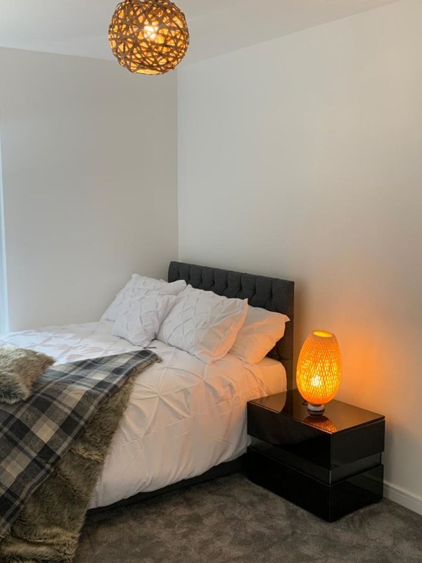 Bedroom with double bed, black headboard, white bedding, pendant light and bedside lamp