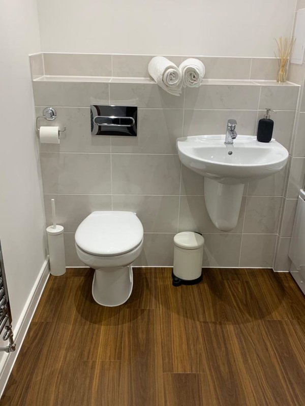 Compact bathroom with toilet, pedestal sink, wall-mounted basin and tiled walls