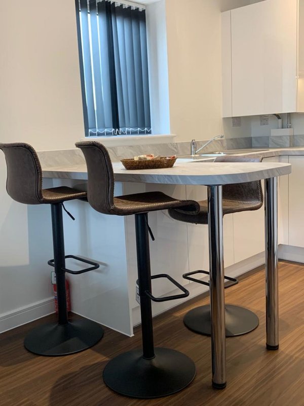 Modern kitchen with breakfast bar, two bar stools, and stainless steel fixtures