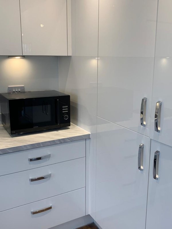 Modern white kitchen with microwave, drawers, and tall storage cabinets