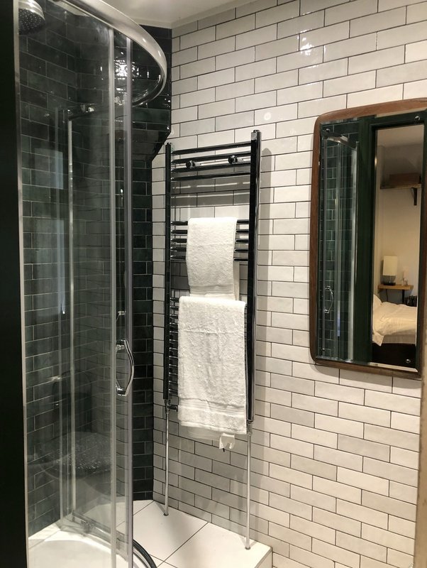 Modern bathroom with white subway tiles, black heated towel rail, and glass shower enclosure