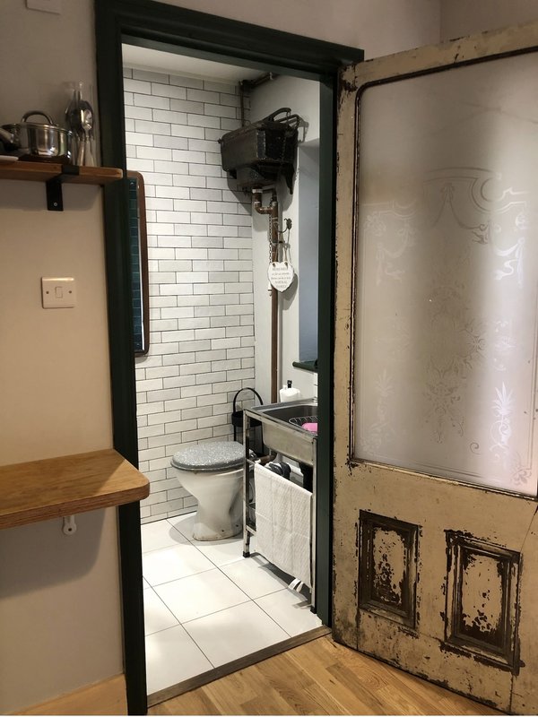 Compact bathroom with white subway tile walls, toilet, sink and shower enclosure
