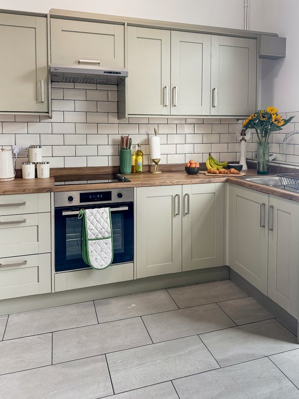 Modern kitchen with cream cabinets, subway tile splashback, wooden countertop and integrated appliances