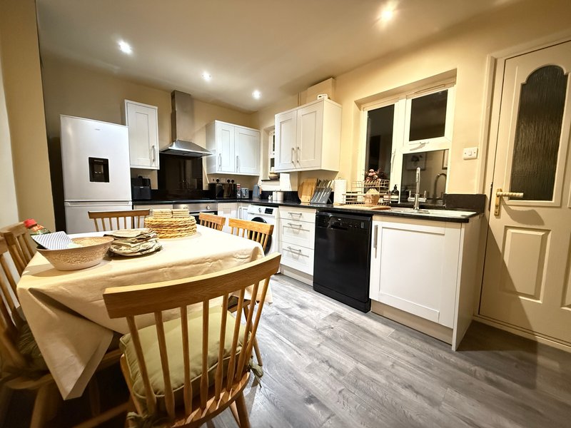 Open-plan kitchen and dining area with white cabinetry, black oven, wooden table and chairs
