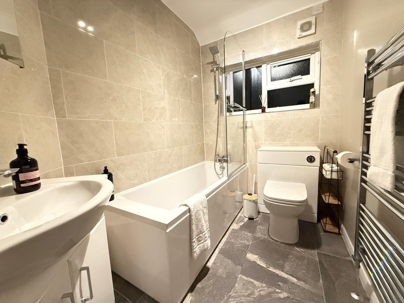 Modern bathroom with bathtub, sink, toilet, heated towel rail and window