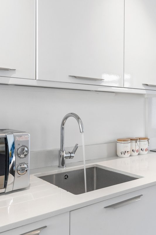 Modern white kitchen with stainless steel sink, chrome tap and white cabinetry