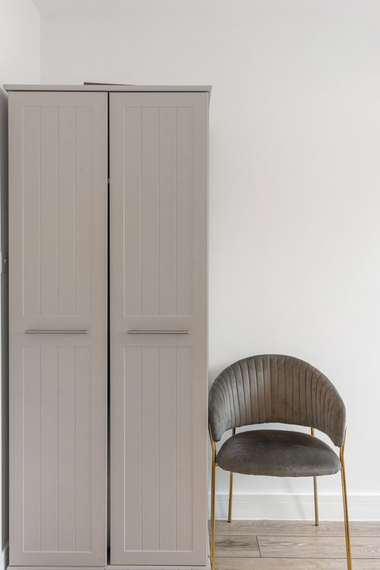 Minimalist bedroom interior with tall wardrobe and modern curved chair