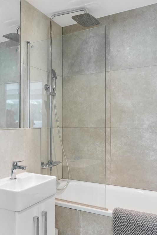 Modern bathroom with walk-in shower, white sink, grey tile walls and rainfall showerhead