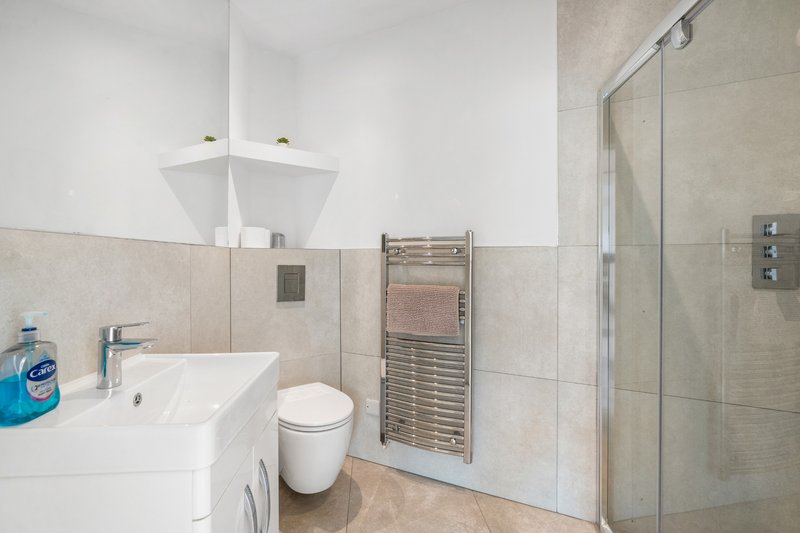 Modern bathroom with white sink, toilet, heated towel rail and walk-in shower