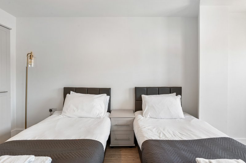 Twin bedroom with two single beds, white pillows, dark headboards and wooden floor