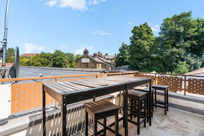 Rooftop terrace with dining table, chairs, and views over residential buildings