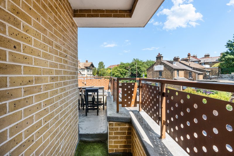 Brick terrace with outdoor seating area, decorative brown screen, and neighboring rooftops visible