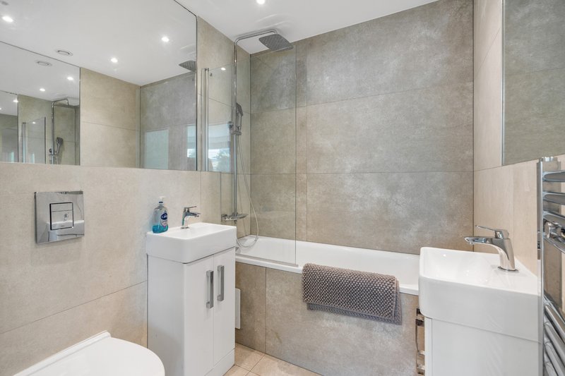 Modern bathroom with white vanity, toilet, bathtub, glass shower screen and heated towel rail