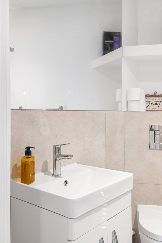 Modern bathroom with white vanity sink, beige tile backsplash and mirror