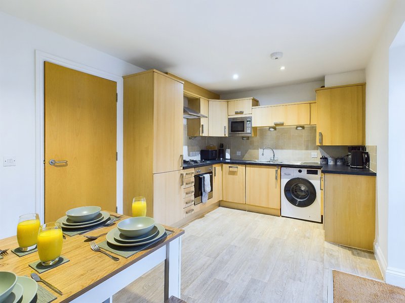 Modern kitchen with yellow cabinetry, dining table, washing machine and integrated appliances