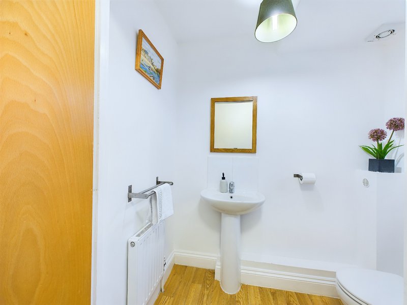 Bathroom with pedestal sink, gold-framed mirror, pendant light and wooden flooring