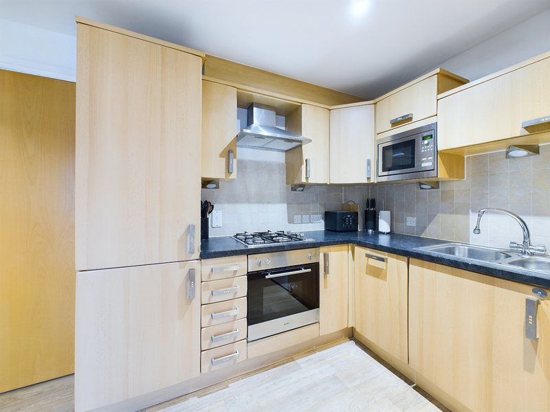 Modern kitchen with light wood cabinets, black countertop, gas hob and integrated appliances