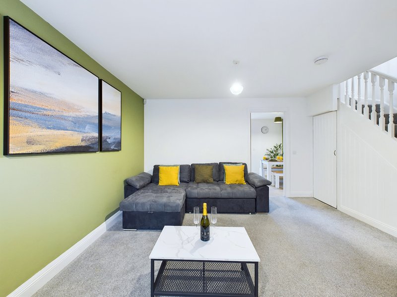 Living room with lime-green accent wall, gray sectional sofa, yellow cushions, and white coffee table