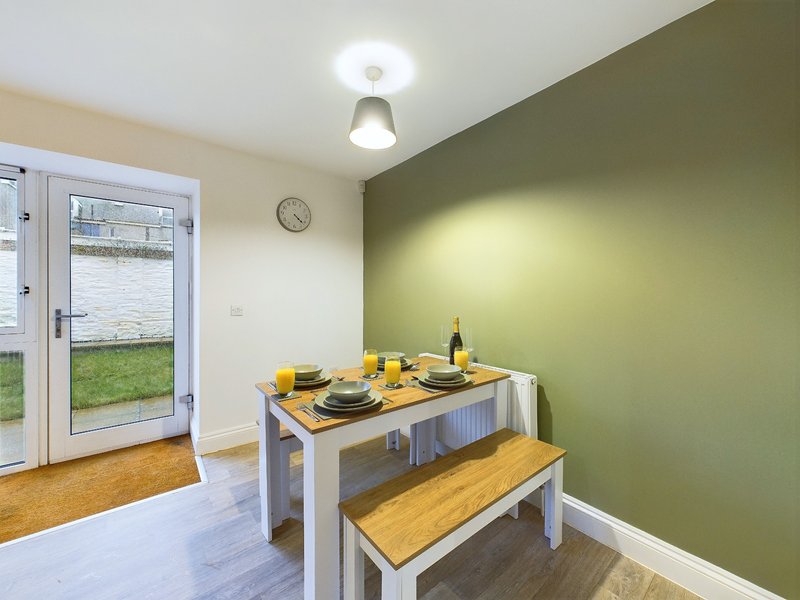 Dining area with table, bench seating, and bottle on surface, green accent wall