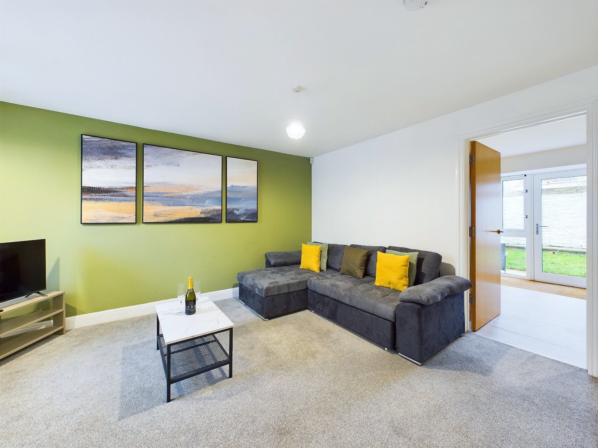 Modern living room with lime green accent wall, grey sectional sofa, yellow cushions, framed landscape art